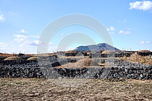 View of Jeju Island`s traditional form of graves surrounded by rocks for blocking the strong winds of Jeju Island, South Korea