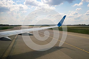 View of jet airplane wing taxiing runway after landing at airport. Travel and air transportation concept