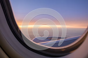 View of jet engine of airplane  from window seat with cloudy sky in sunset light