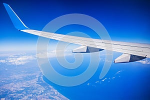 View of jet plane wing with blue sky