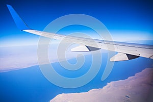 View of jet plane wing with blue sky