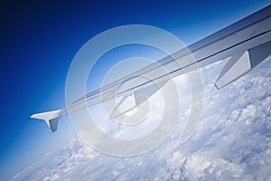 View of jet plane wing with cloud patterns