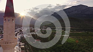 View on Kemer city and islamic mosque with mountains and sunset on background filmed by drone
