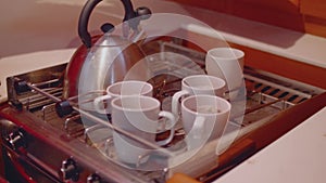 View of kettle and cups with tea and coffee on cooker hanging on cardan and swaying because of motion