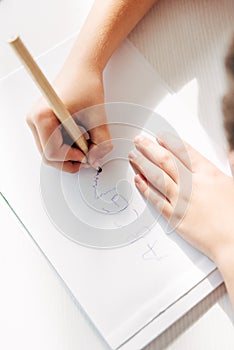 View of kid with dyslexia drawing on paper with pencil