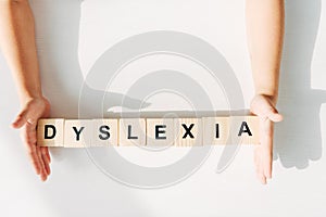 View of kid with dyslexia holding wooden cubes with lettering