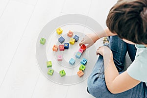 View of kid with dyslexia playing with colorful building blocks