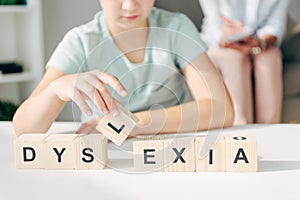 View of kid with dyslexia sitting at table and playing with wooden cubes