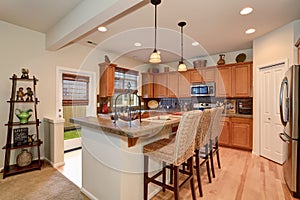 View of kitchen with hardwood storage combination, bar and pendant lights