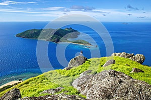 View of Kuata Island from Wayaseva Island with a hiker standing on a rock, Yasawas, Fiji