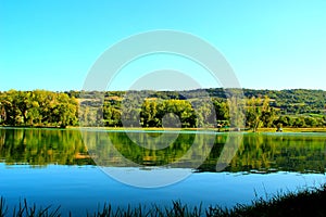 View from Lago Cedri in Lapedona with the surface of water extending over the picture and reflecting vegetation