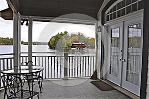 View of the lake from the balcony of the cottage. Across the water is a cottage nestled among green trees