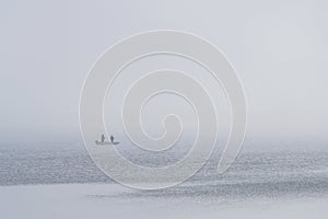 view of the lake and a boat with anglers in the fog