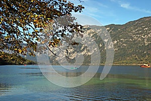 View of Lake Bohinj in Eslovenia, with canoes, a red boat and a mountain in the background. photo