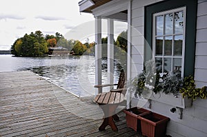 View of the lake from the dock of the boathouse. Across the water is a cottage nestled among green trees