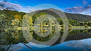 View of the lake, forest, mountains and blue sky with clouds,focus plane in the center.