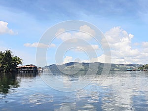 the view of the lake and mountains looks very beautiful and the blue sky and white clouds