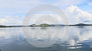 the view of the lake and mountains looks very beautiful and the blue sky and white clouds