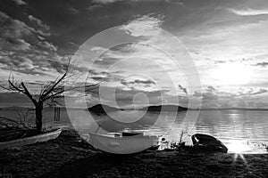 View of a lake shore at almost sunset, with some empty boats, a