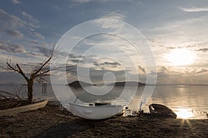 View of a lake shore at almost sunset, with some empty boats, a