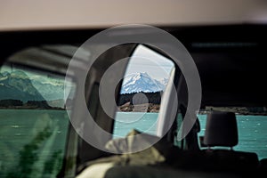 View of a lake and the summit of the beautiful snowy mountain captured from inside a vehicle