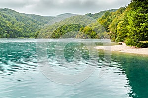 View of lake with turquoise water with sand island with trees