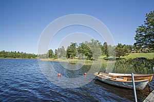 View of lake with two boats parked in shore on blue sky background.