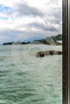 View of the lake through a window with wet glass