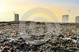 View of the landfill in city against the background of construction residential buildings. Concept of pollution of the air and