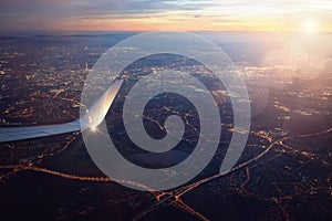 View from landing airplane window of city at sunset