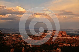 View of the landscape of Bryce Canyon after sunset with the last sunrays still lighting up the clouds above