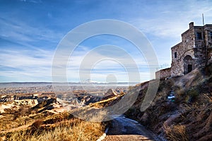 View of the landscape in the Cappadocia valley with strange yellow mountains, rocks, hills, sand road and blue sky background