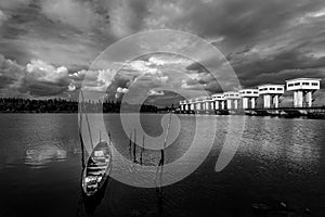View of landscape with fishing boat and water barrier and river with cloud sky storm, Black and white and monochrome style