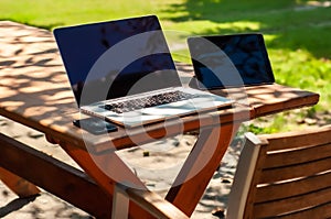 View on a laptop pc and a smartphone and a coffee mug on a table in the garden