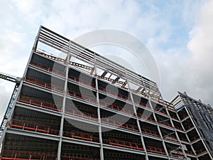 View of a large building development under construction with steel framework and girders supporting the metal floors with b