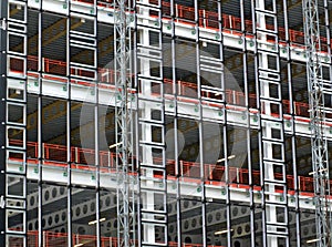 View of a large building development under construction with steel framework and girders supporting the metal floors and hoists