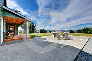 VIew of large concrete floor patio area with table set at backyard photo