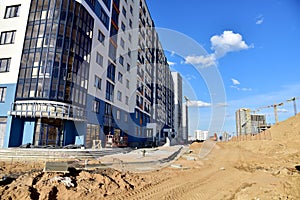 View of a large construction site with buildings under construction and multi-storey residential homes.Tower cranes in action on
