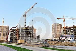 View of large construction site. Tower cranes in action. Formworks and pouring concrete through a Ñoncrete pump truck connected