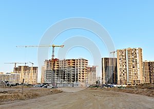 View of a large construction site where tower cranes and heavy construction equipment are building multi-storey residential