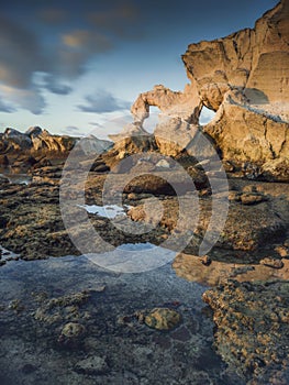 View of a large rock with a hole on the beach when the sea water recedes