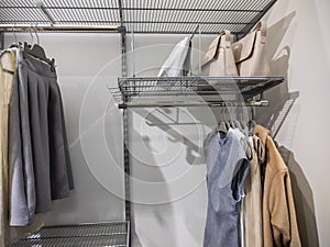 View of a large, walk in closet with metal organizing racks, storing dresses, skirts, jackets, and purses inside of it