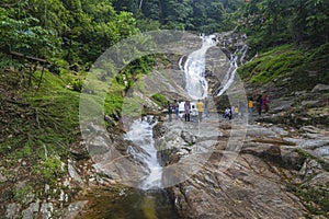 The view of Lata Iskandar Falls cascading down over and flowing between granite boulder with people at Cameron Highlands,