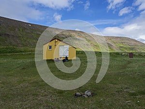 View on latrar camp site in adalvik cove with yellow emergency shelter cabin in west fjords Hornstrandir in Iceland photo