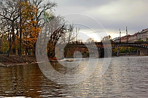 View of Legion bridge over Vlatava river lined with autumn trees in Prague, Czech Republi