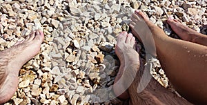 View of legs of young girl and boy on croatian beach, pebble beach, lower part of human body