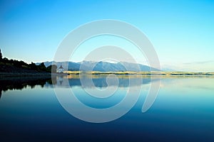 View on level water in dam Liptovska Mara with the background of the Havranok church and West Tatras mountains. Beautiful Slovak s