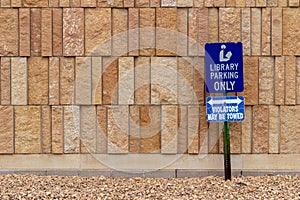 View of a library parking sign in front of an modern limestone wall with rough texture bricks