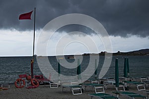 View of lifeguard chair with beach loungers under a stormy sky in Golfo Marinella Sardinia, Italy