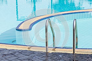 View of a light clear blue swimming pool with steel ladder.